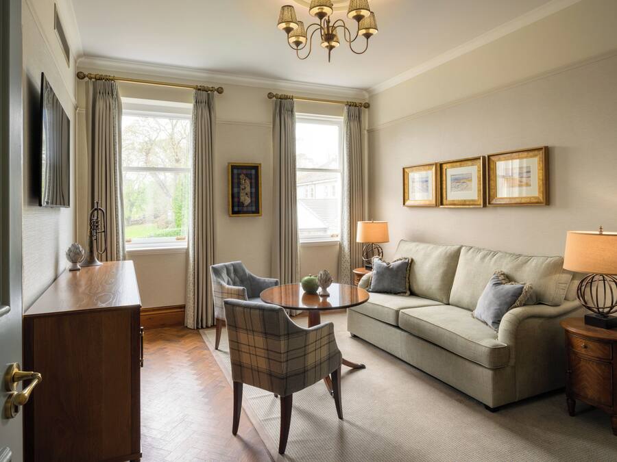Un salon comprenant un canapé, des fauteuils, une table basse, une lampe et un téléviseur.