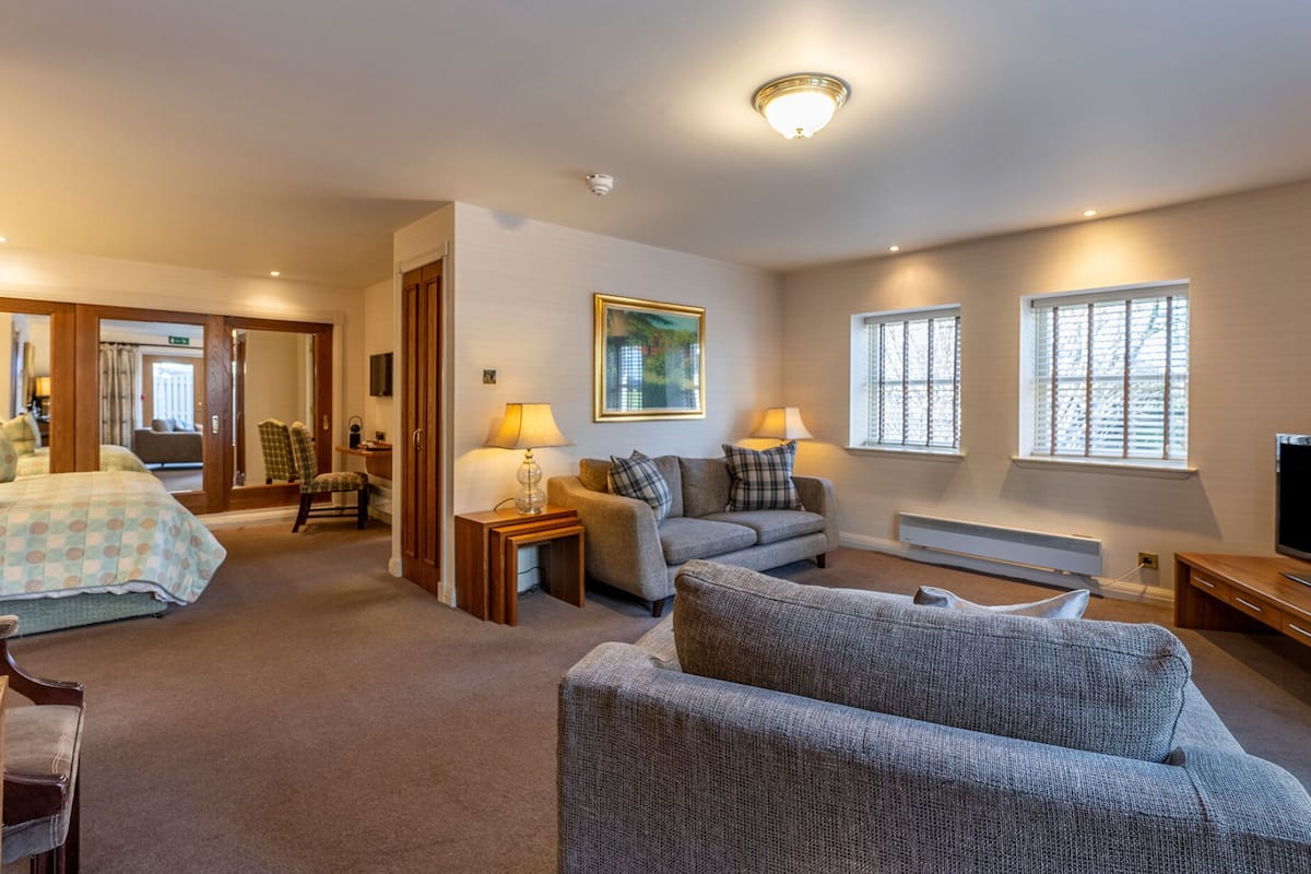 A hotel room with a bed, a sofa, a TV, and a desk with a chair.
