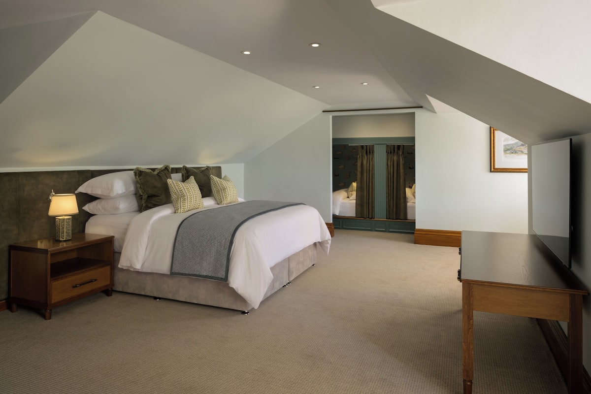 A bedroom with a bed, nightstand, TV, and a mirror.