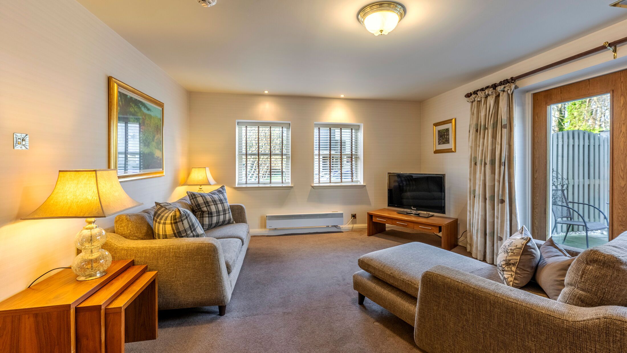 A living room with a sofa set, a TV, a heater, and a window with blinds.