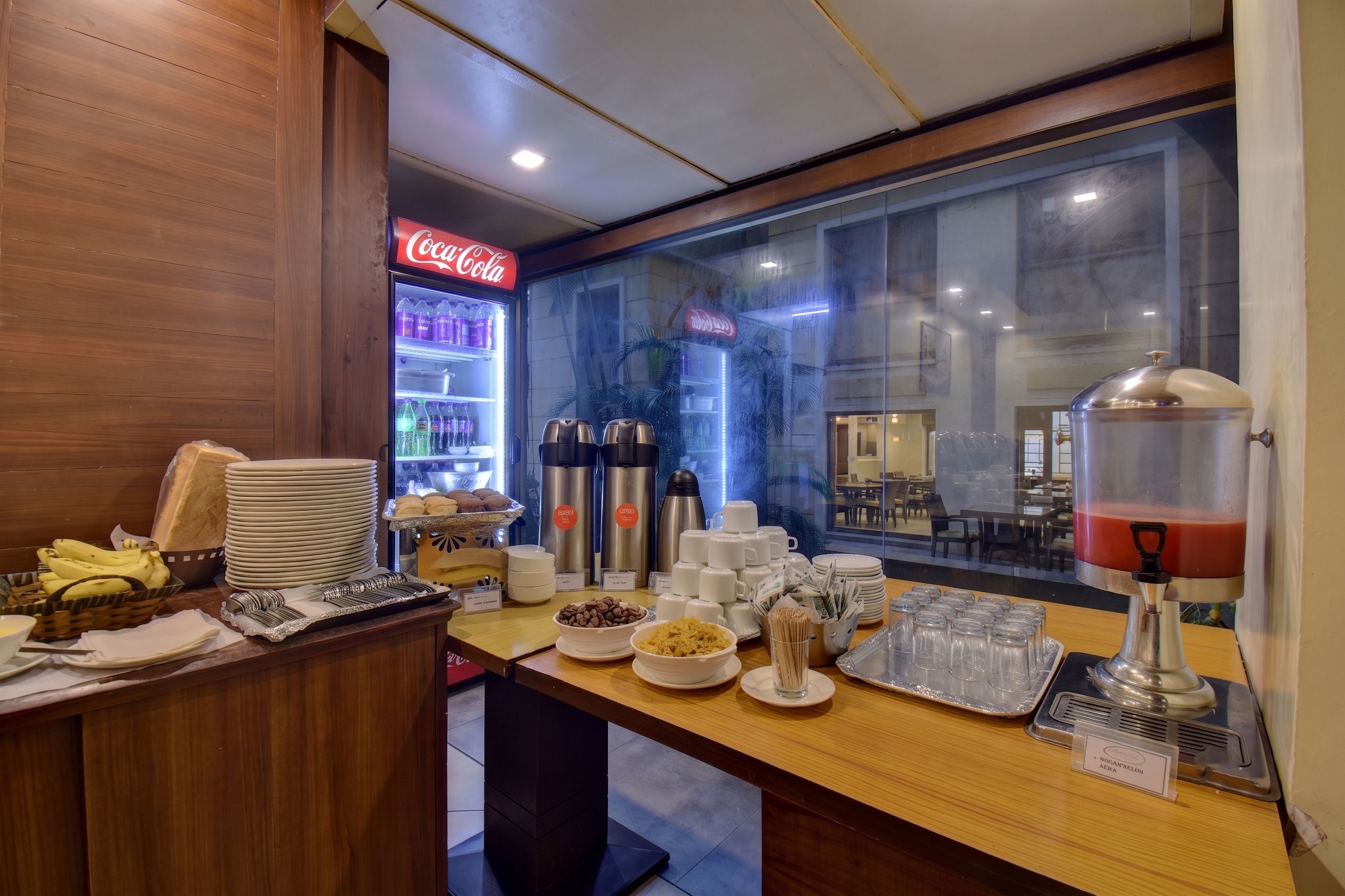 Un buffet de petit-déjeuner proposant divers plats et un réfrigérateur rempli de Coca-Cola.