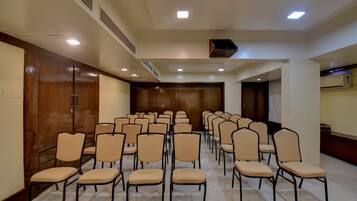 A conference room with rows of chairs, a wooden door, and ceiling vents.