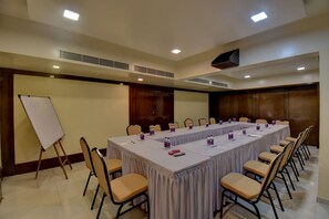 A conference room with a long table, chairs, a whiteboard, and ceiling vents. - Hotel Lotus Ivy Studios,Near Pune Airport (Pune)