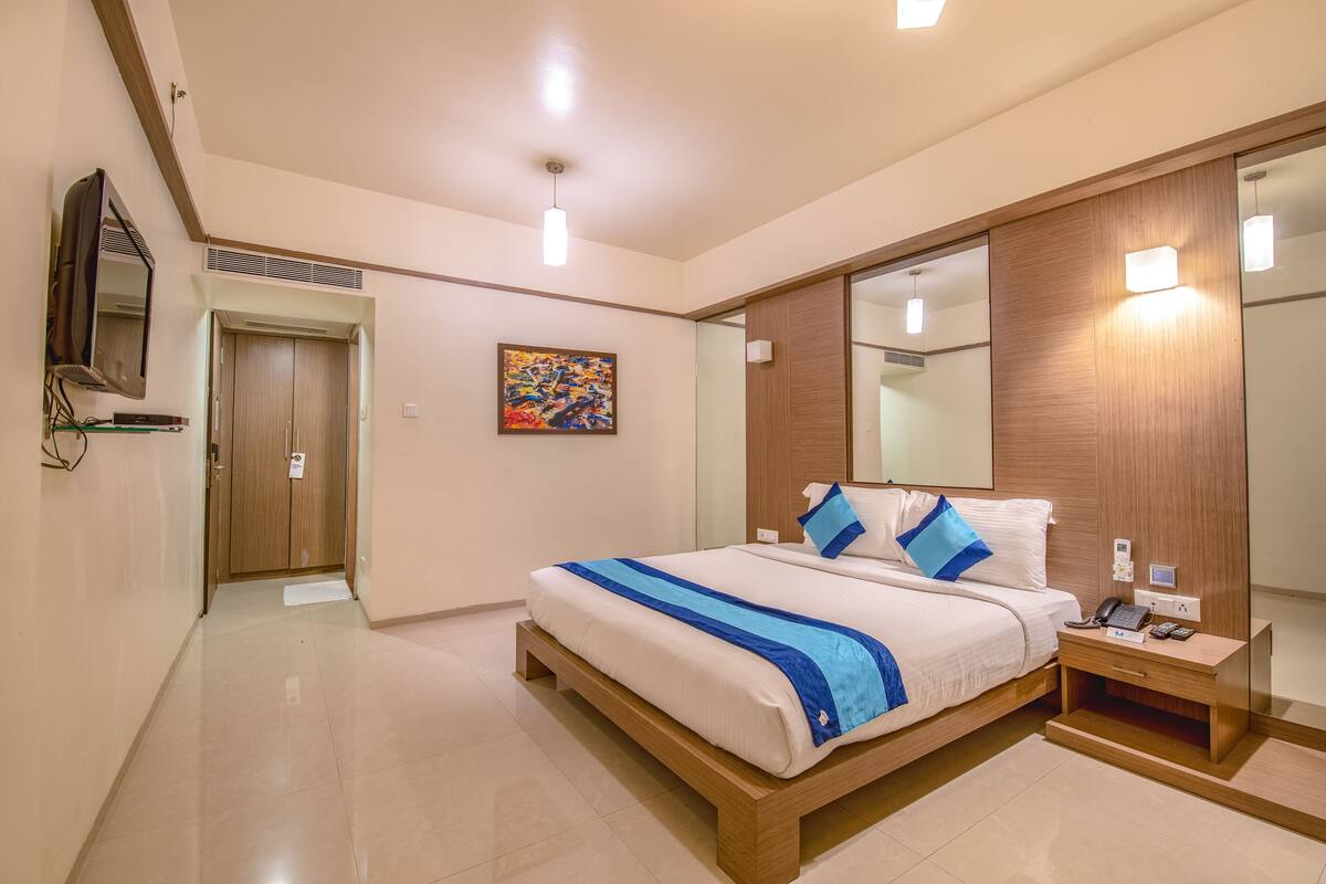 Una habitación de hotel moderna con una cama grande, una mesita de noche y un espejo.