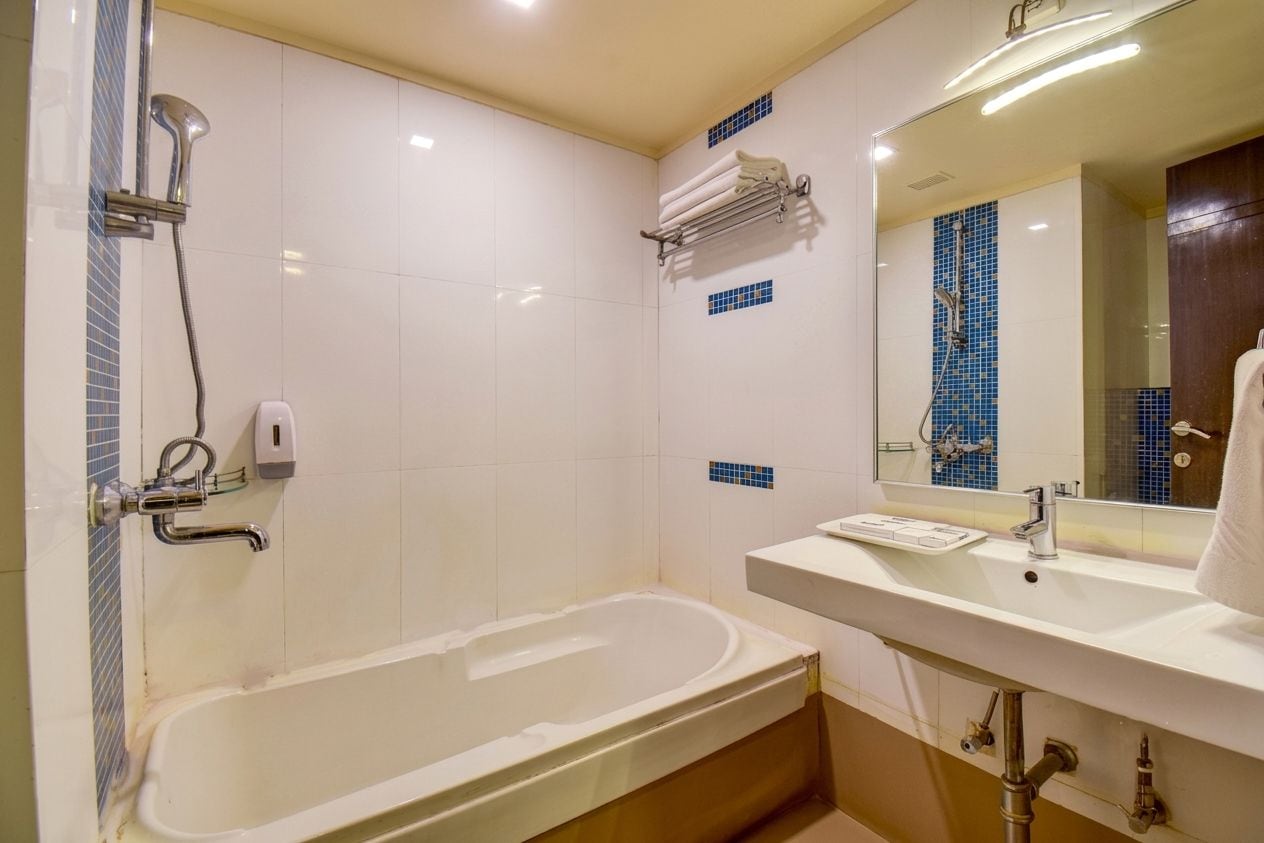 A bathroom with a bathtub, a sink, a mirror, and a towel rack.