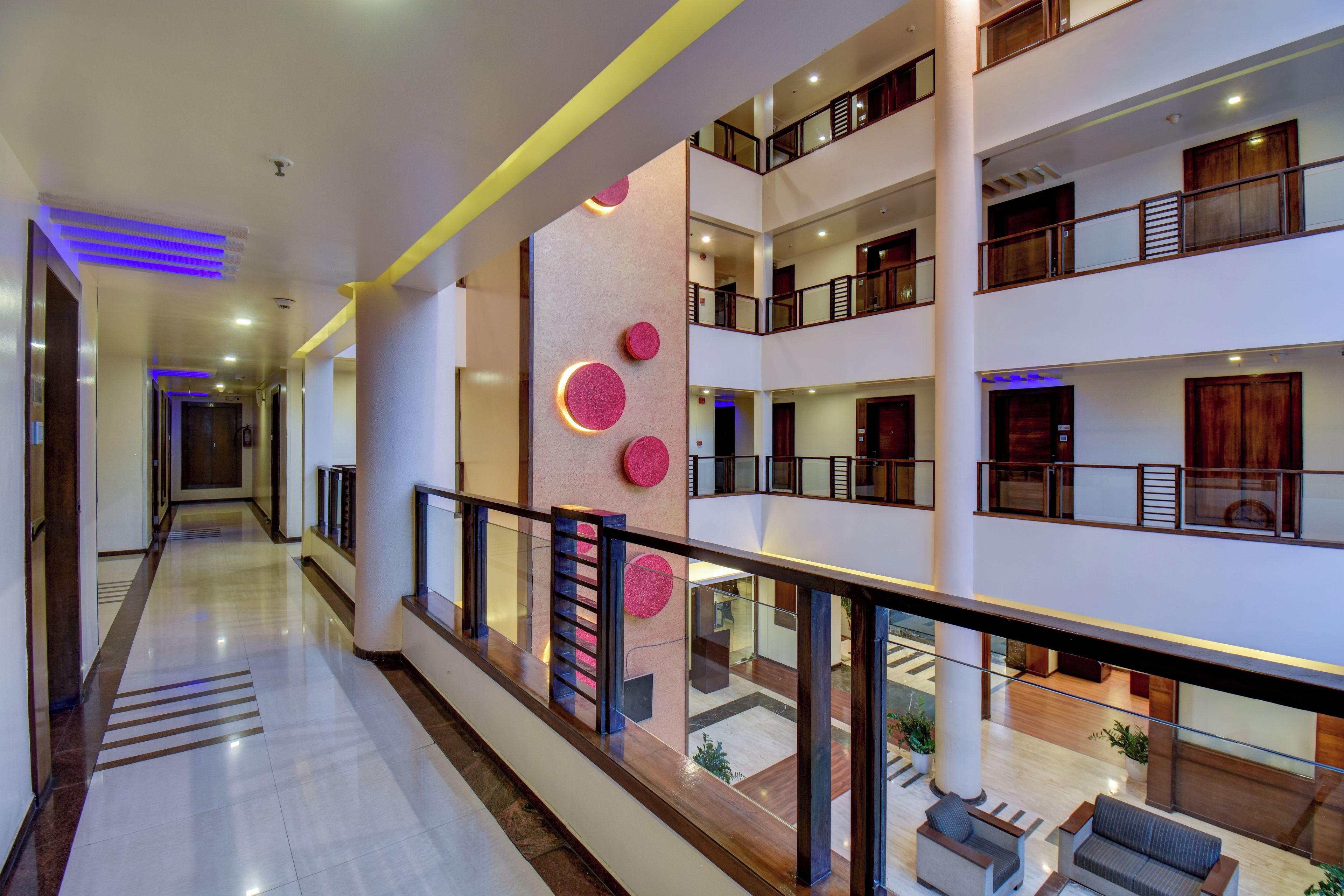Un hôtel à plusieurs niveaux, avec un atrium central, des rampes en verre et un design moderne.