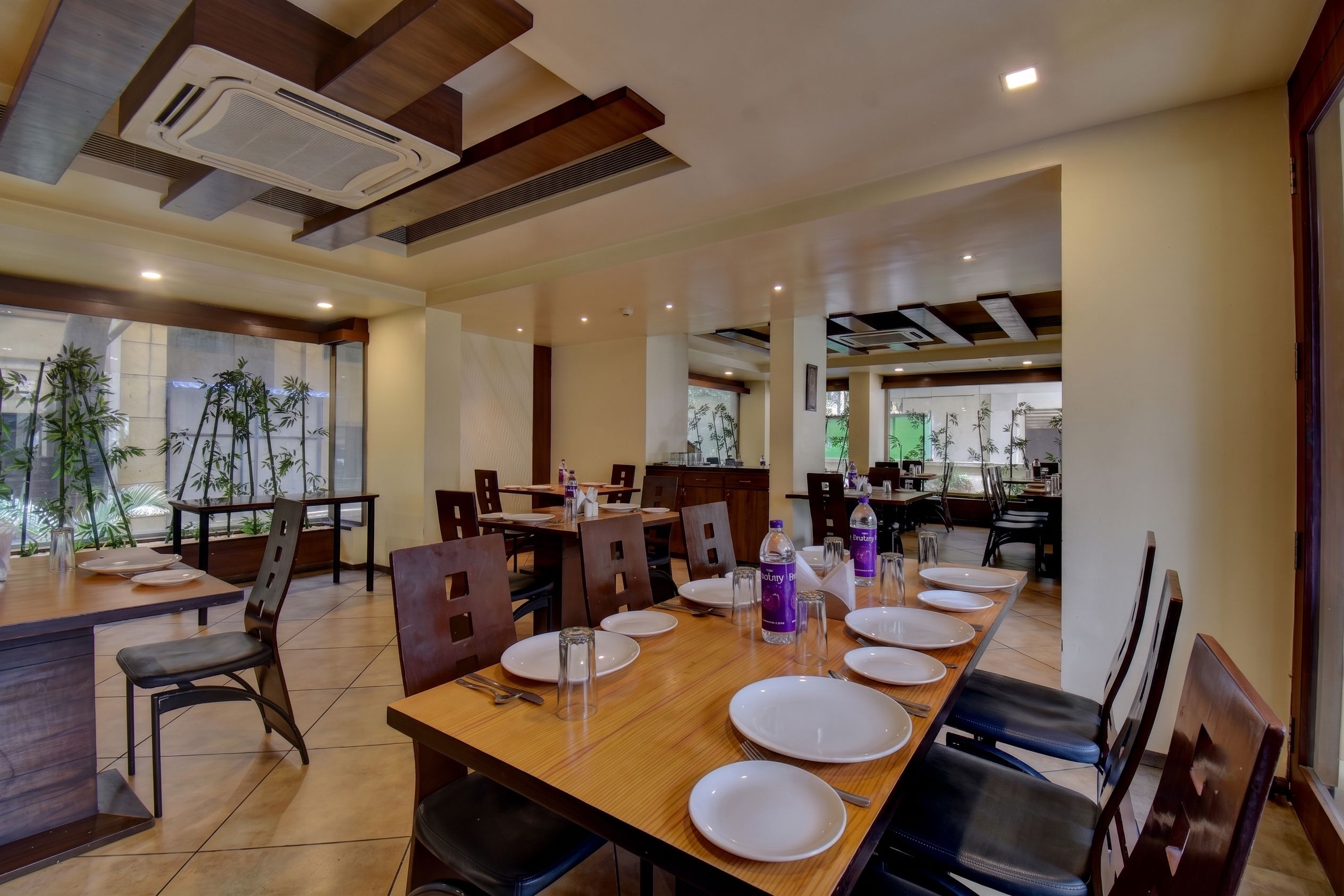 A dining area with tables set for four, chairs, and a view of the outdoors.
