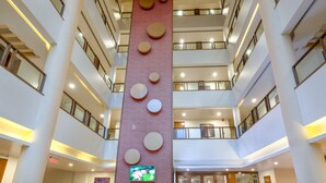 A multi-level atrium with a central column, balconies, and a large screen displaying an image. - Ivy Studios Hotel Near Pune Airport (Pune)