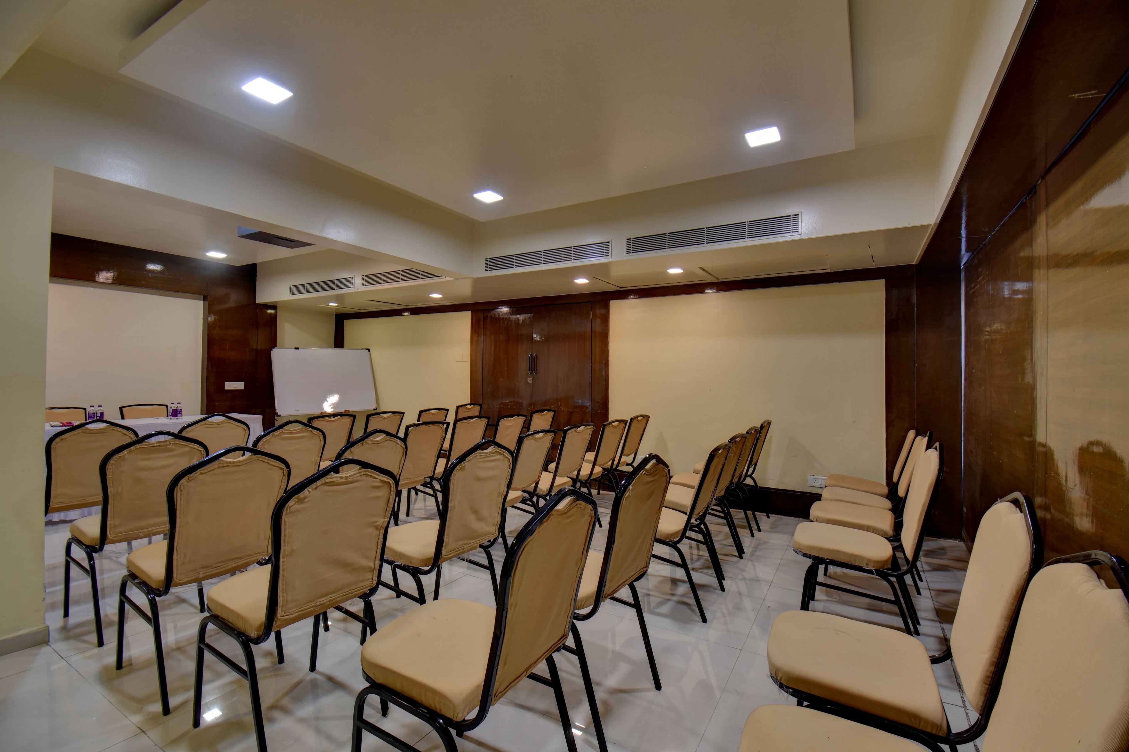 A conference room with rows of chairs, a whiteboard, and ceiling vents.