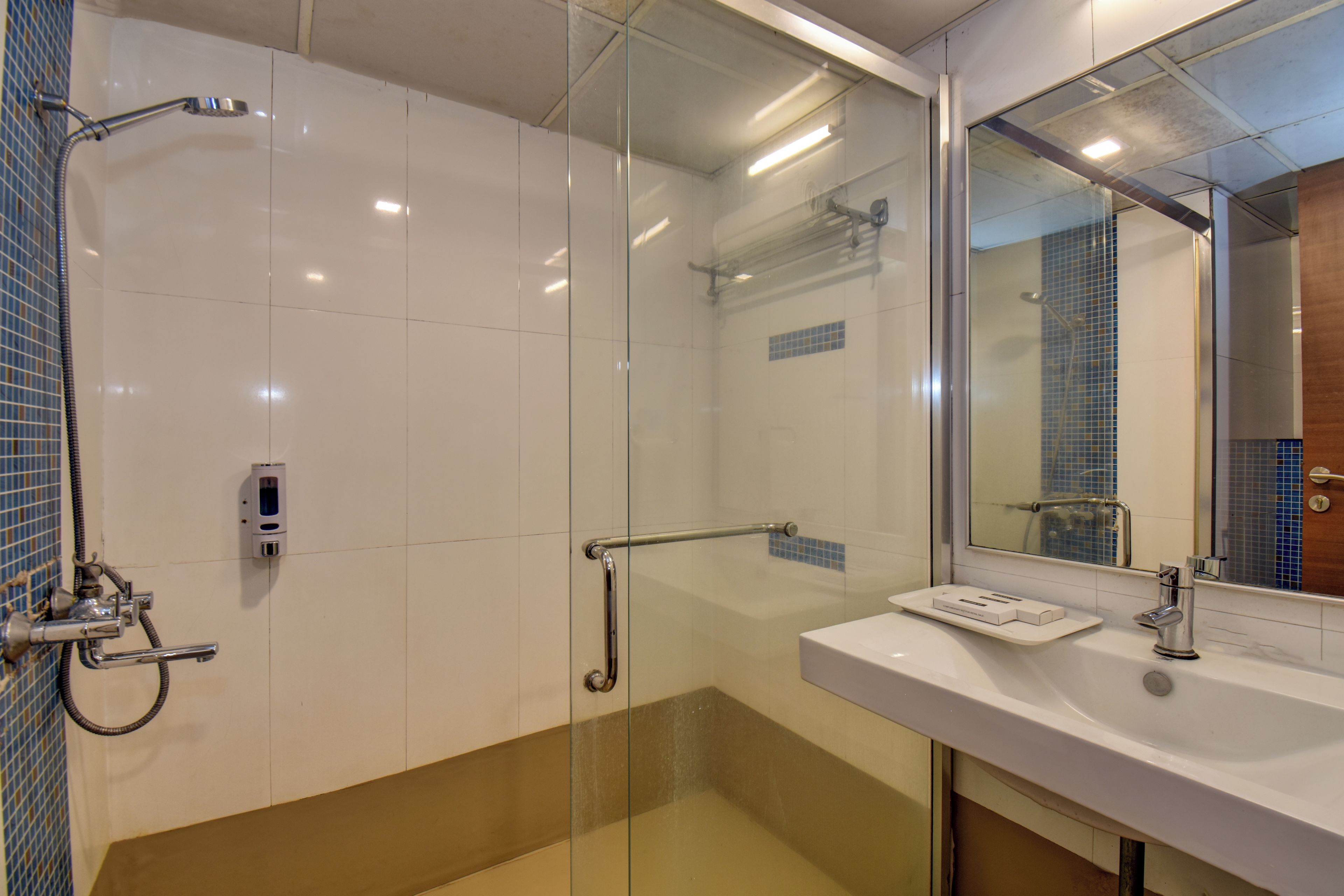 A modern bathroom with a glass shower enclosure, a white sink, and a mirror above the sink.