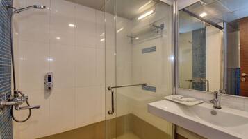 A modern bathroom with a glass shower enclosure, a white sink, and a mirror above the sink.