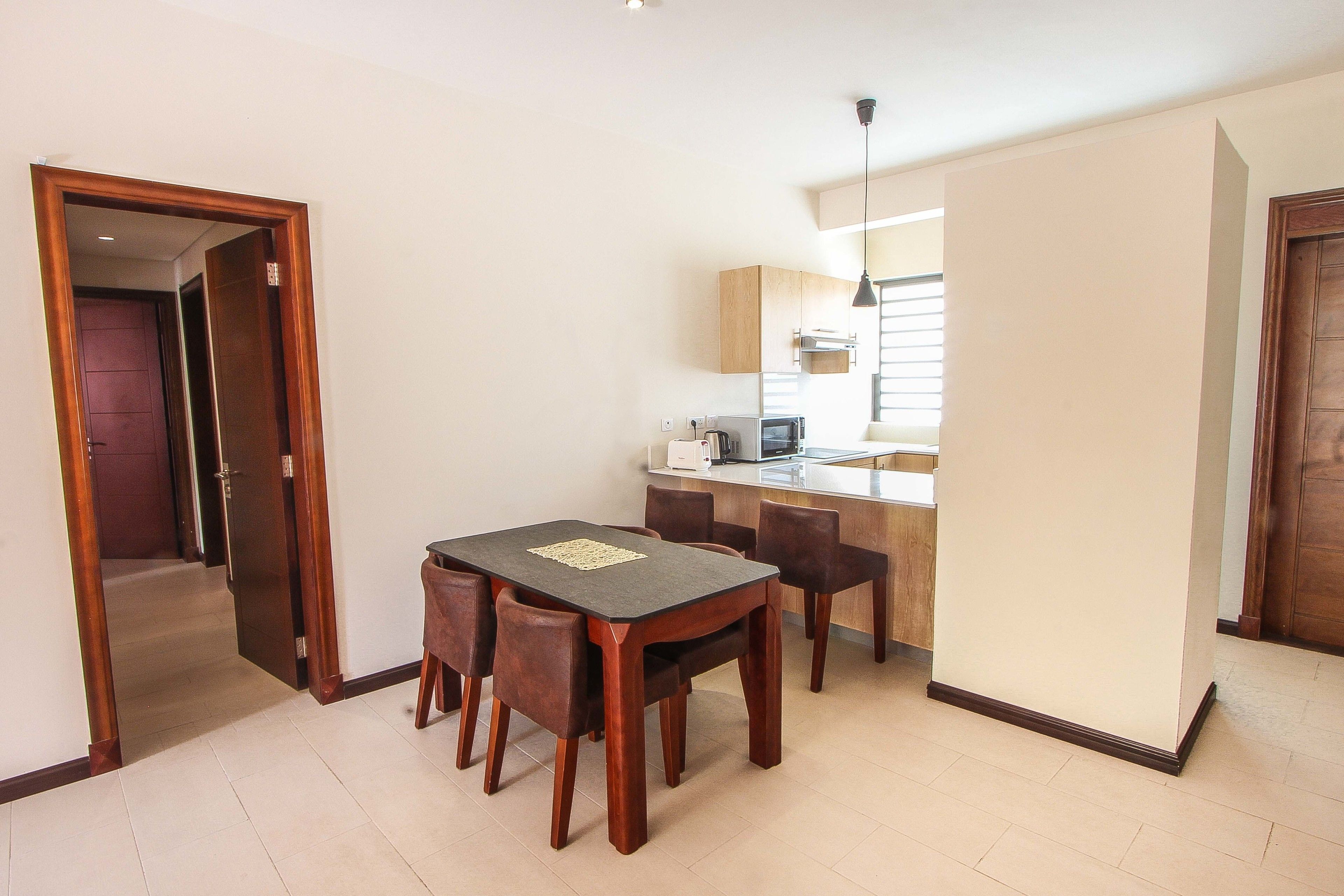 A compact living space with a dining area, kitchenette, and a door leading to another room.