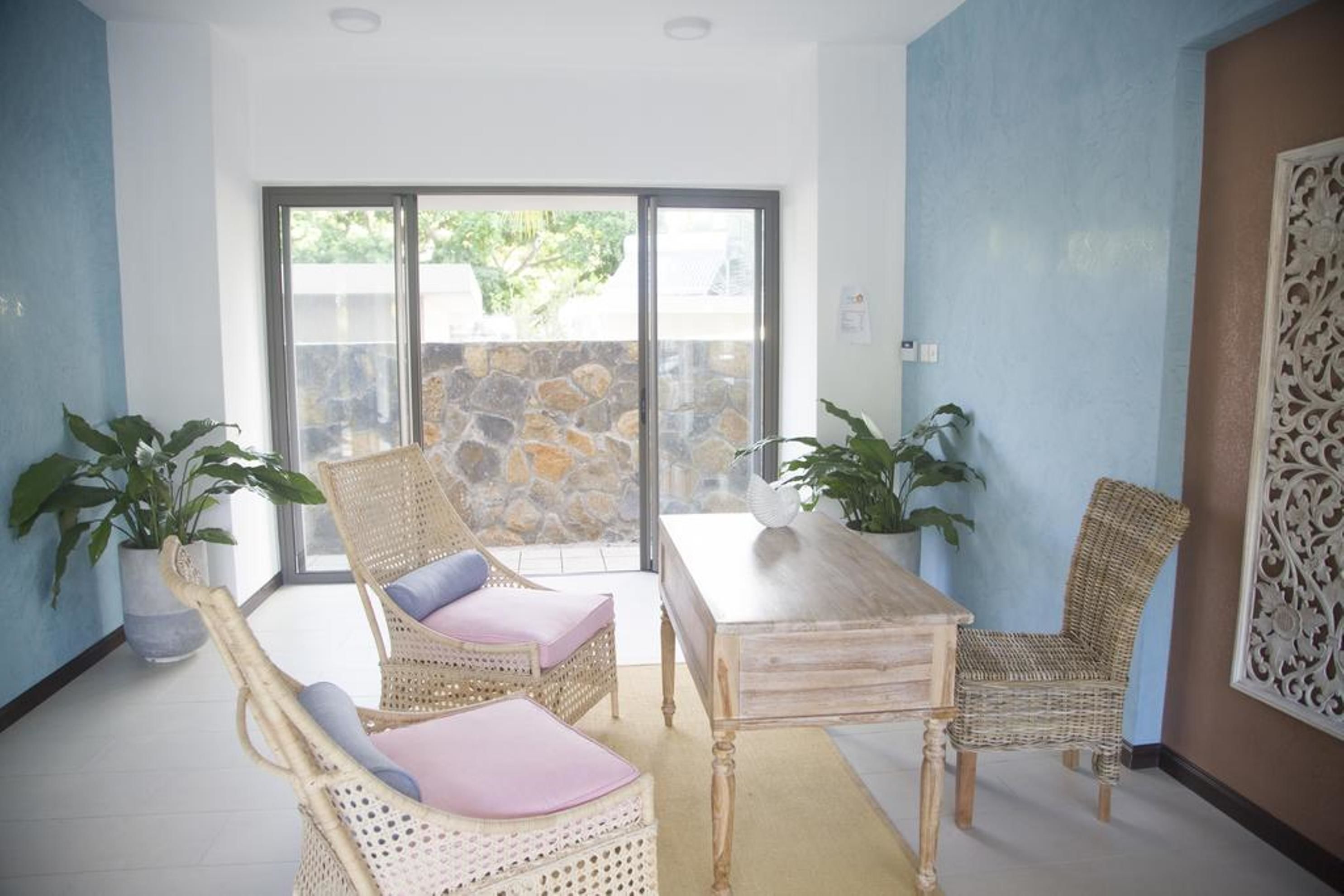 Una habitación con muebles de mimbre, una mesa de madera y plantas en macetas.