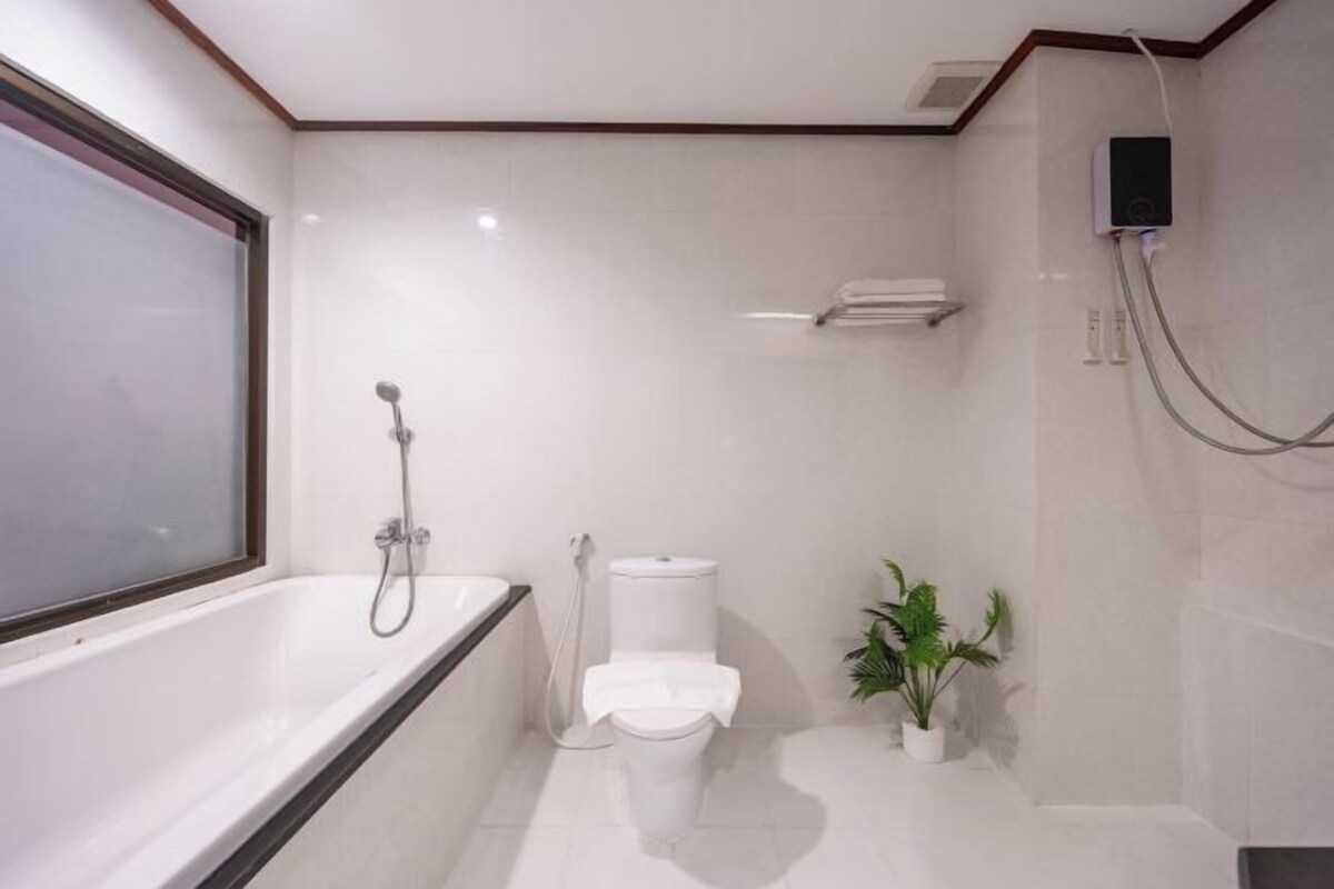 A modern bathroom with a bathtub, toilet, and shower.