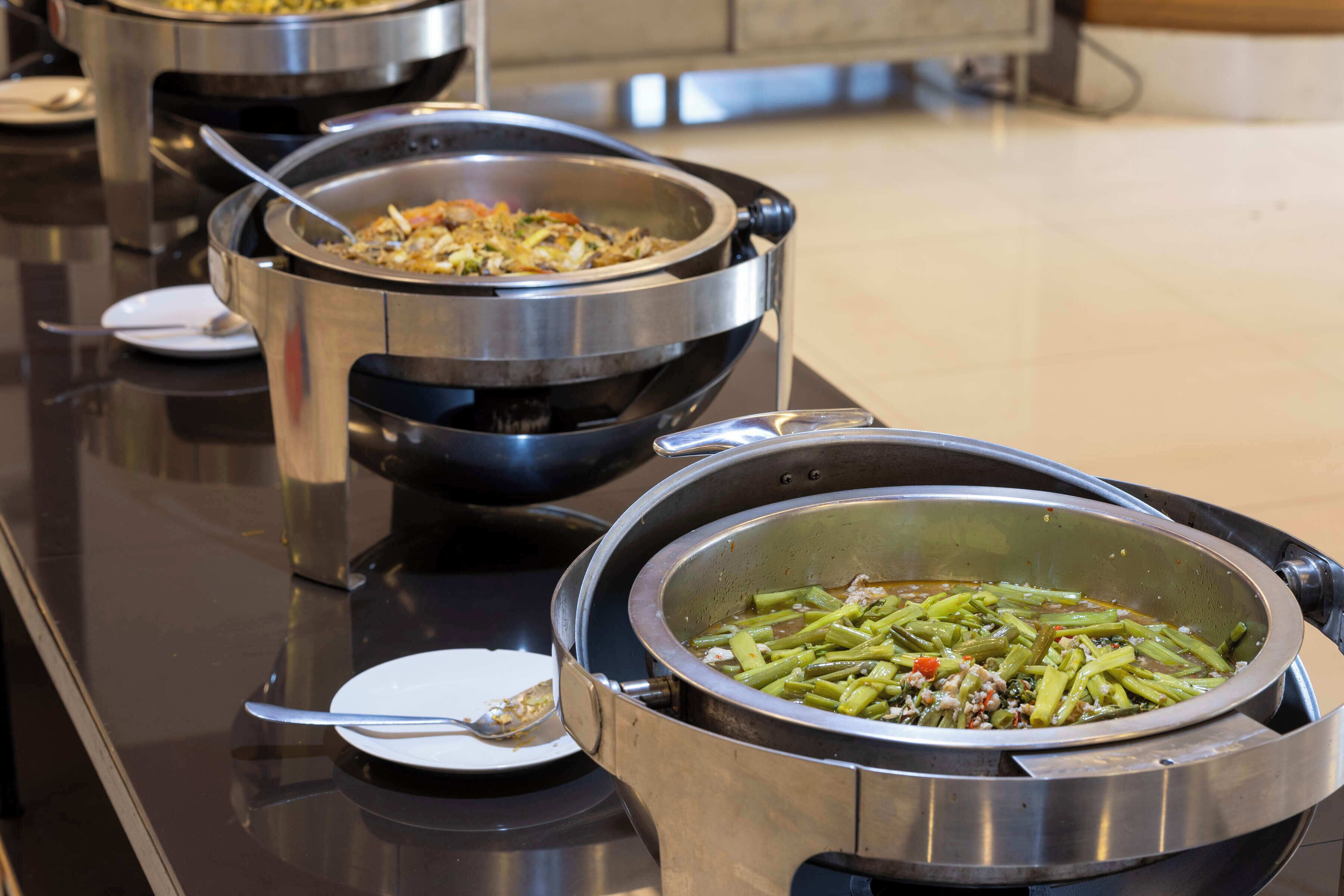 A buffet with multiple stainless steel serving dishes containing various dishes.