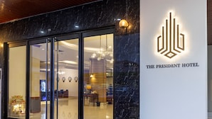 L'esterno dell'Hotel The President, con una facciata moderna, ampie porte in vetro e un logo ben visibile.