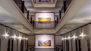 Un interno su più livelli con una scala centrale, ringhiere in legno e opere d'arte alle pareti.