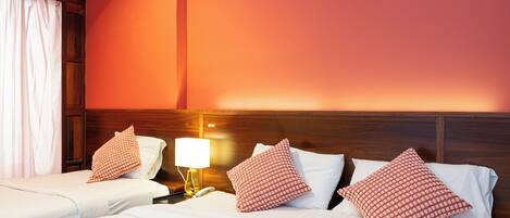 A hotel room with two beds, a nightstand with a lamp, and a wooden headboard.