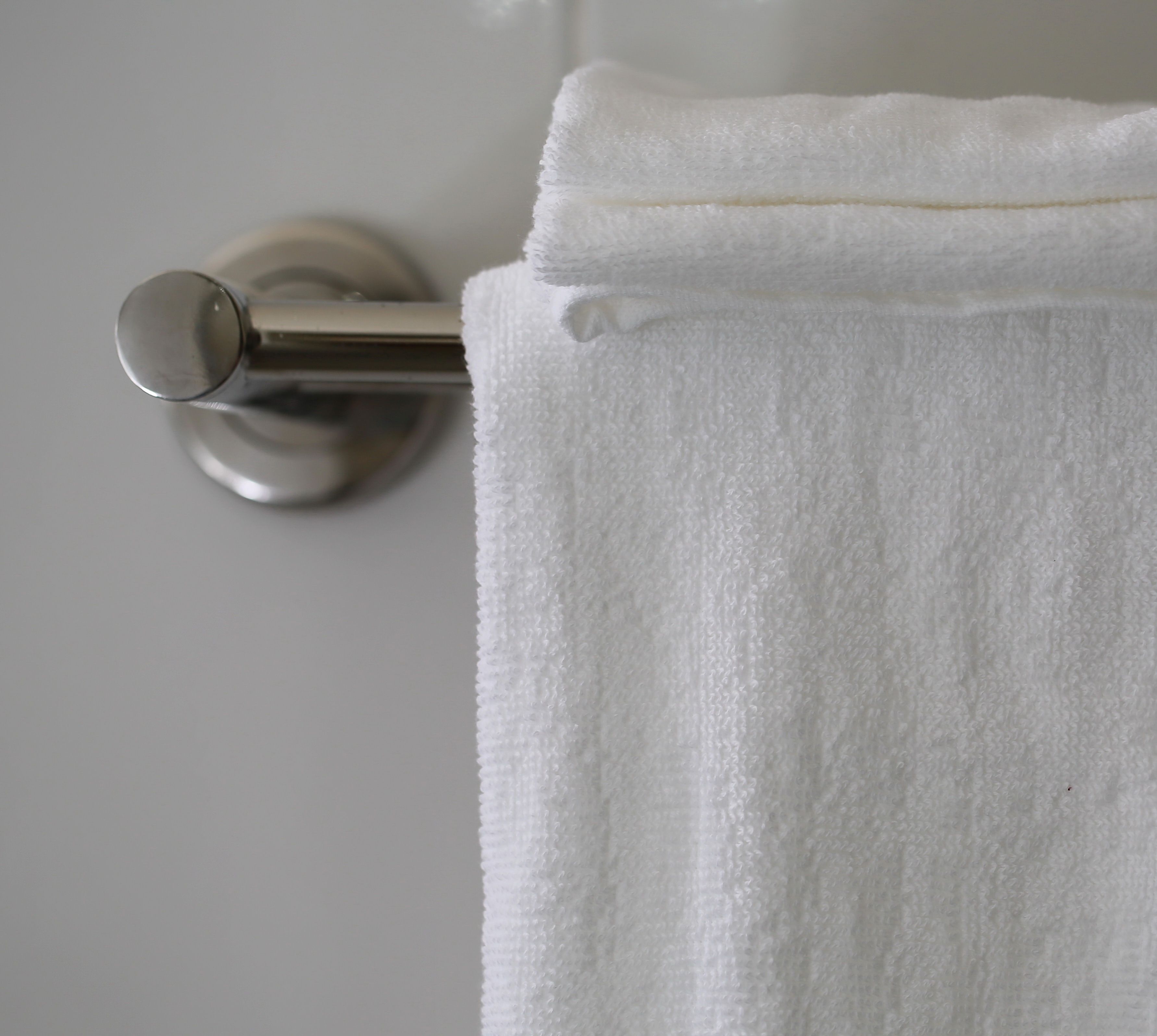 Une serviette blanche est suspendue à une barre à serviettes en métal.