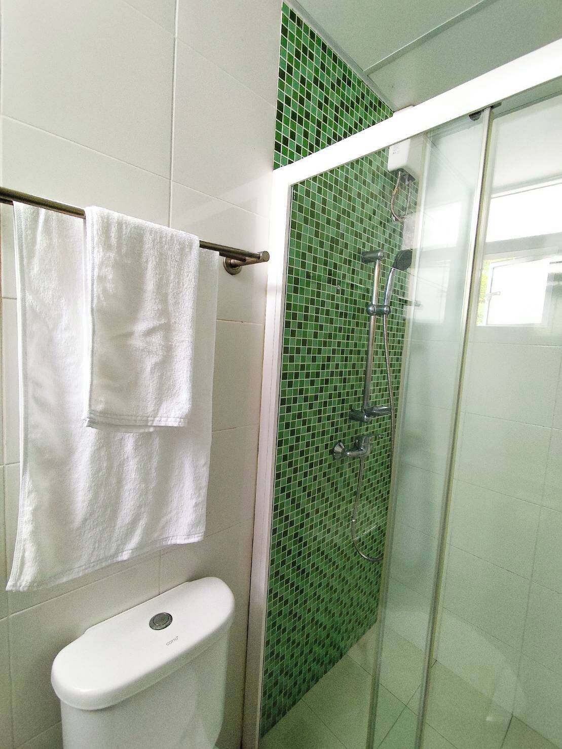 Ein Badezimmer mit Toilette, einer Duschkabine aus Glas und einem Handtuchhalter.