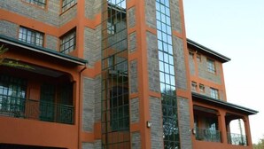 A multi-story building with a prominent vertical glass facade and a sign reading "PEC HOUSE". - PEC Guest House (Ngong)