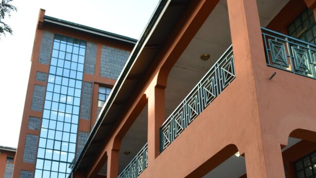 A multi-story building with a balcony, large windows, and potted plants. - PEC Guest House (Ngong)