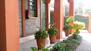 A building with a paved walkway and potted plants along the side. - PEC Guest House (Ngong)