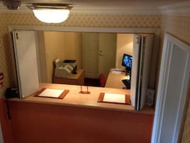 Zona de recepción de un hotel con mostrador, un monitor de computadora y un teléfono.