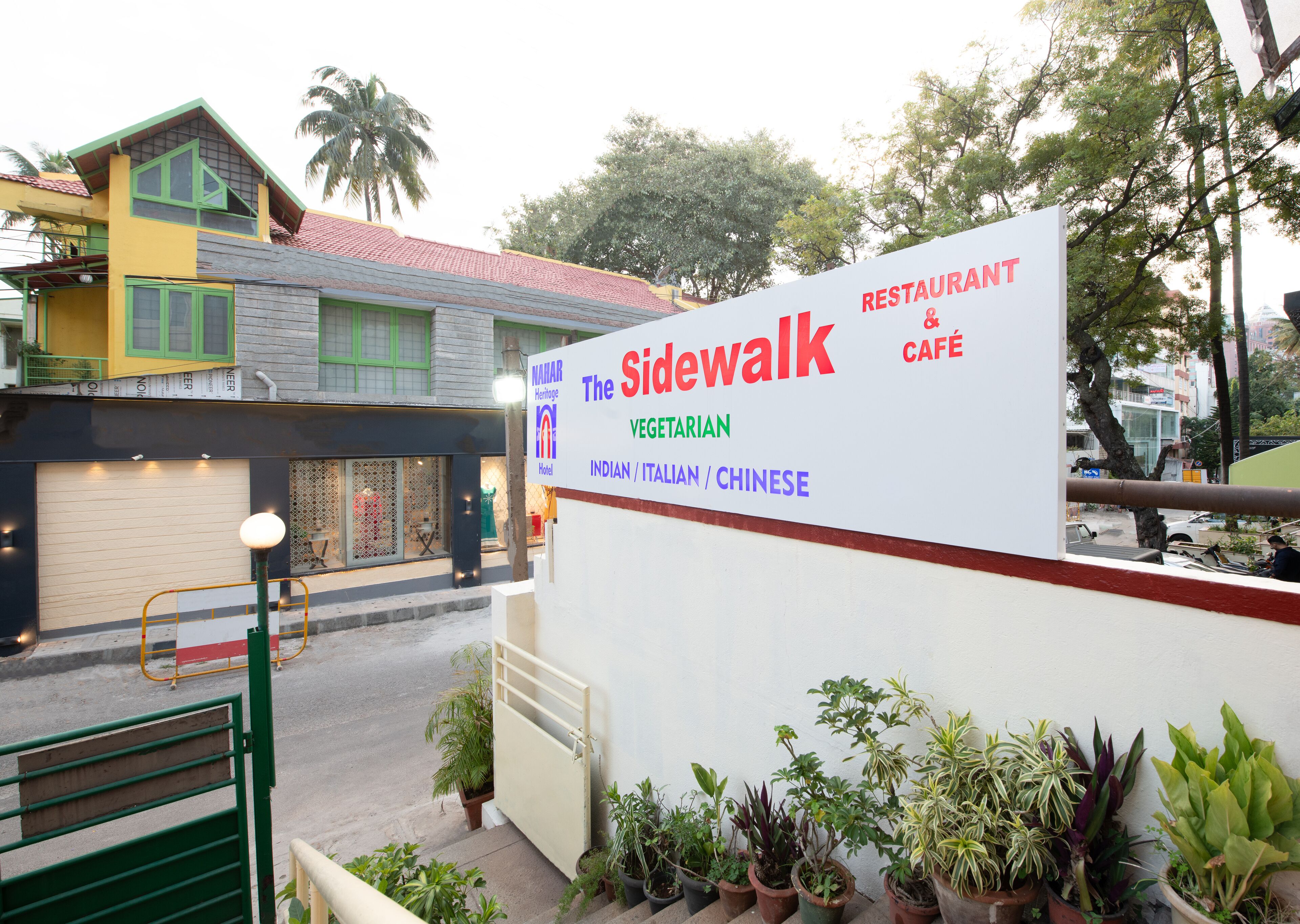 Señal del restaurante y cafetería 'The Sidewalk', que indica que sirve cocina india, italiana y vegetariana.