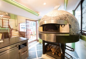 A stone oven with a digital clock, a wooden counter, and a tiled floor. - Nahar Heritage Hotel (Bengaluru)