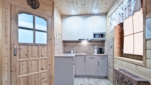 A modern kitchen with wooden cabinetry, a microwave, and a sink. - Domki z Widokiem (Zakopane)