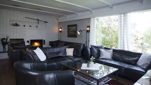 En moderne stue med pejs, lædersofaer og et sofabord i glas.