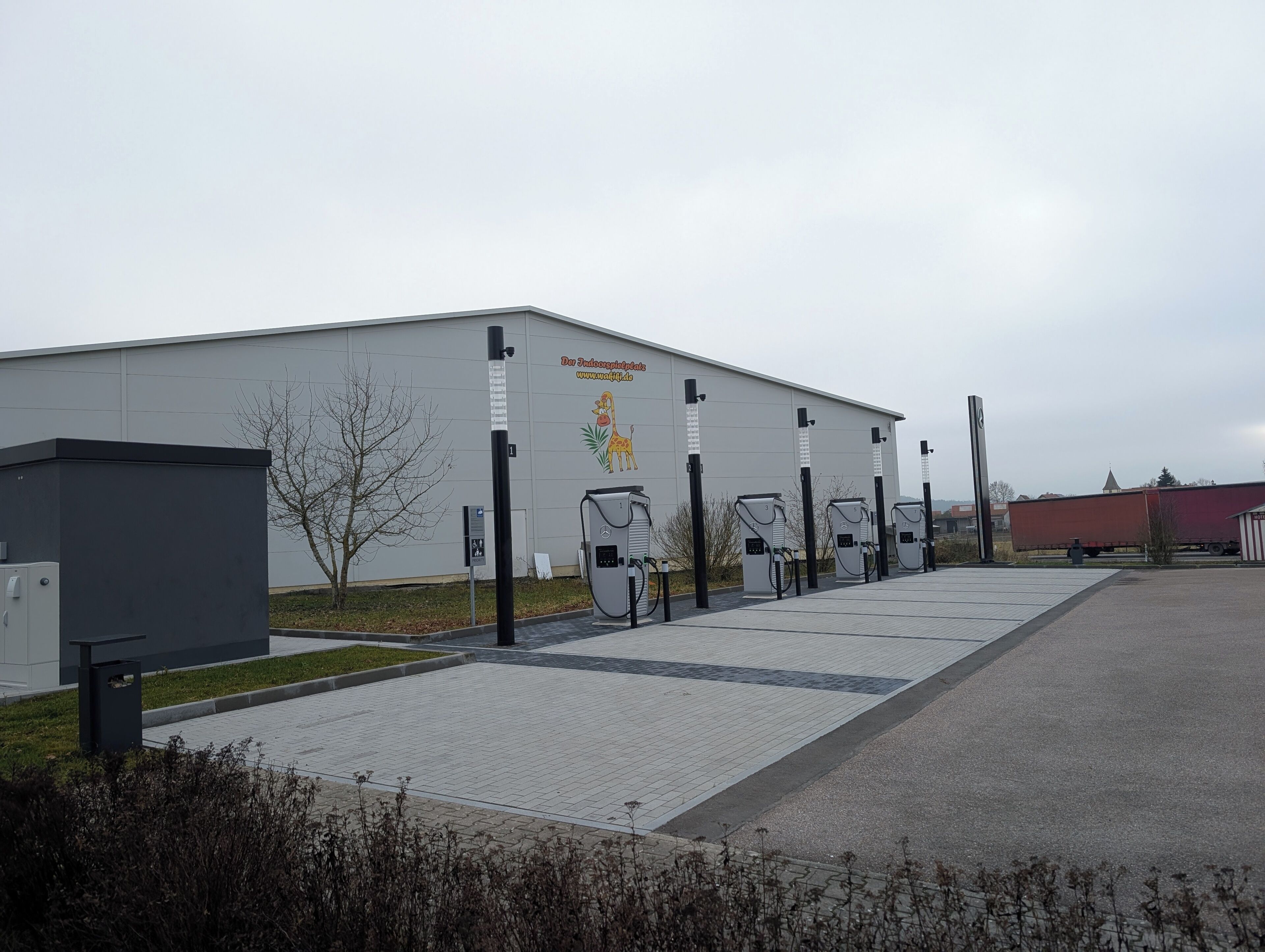 A large industrial building with a mural of a giraffe and a website address.