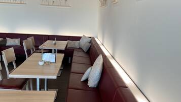 Ein modernes Restaurant mit Holztischen und roten Sitzgelegenheiten.