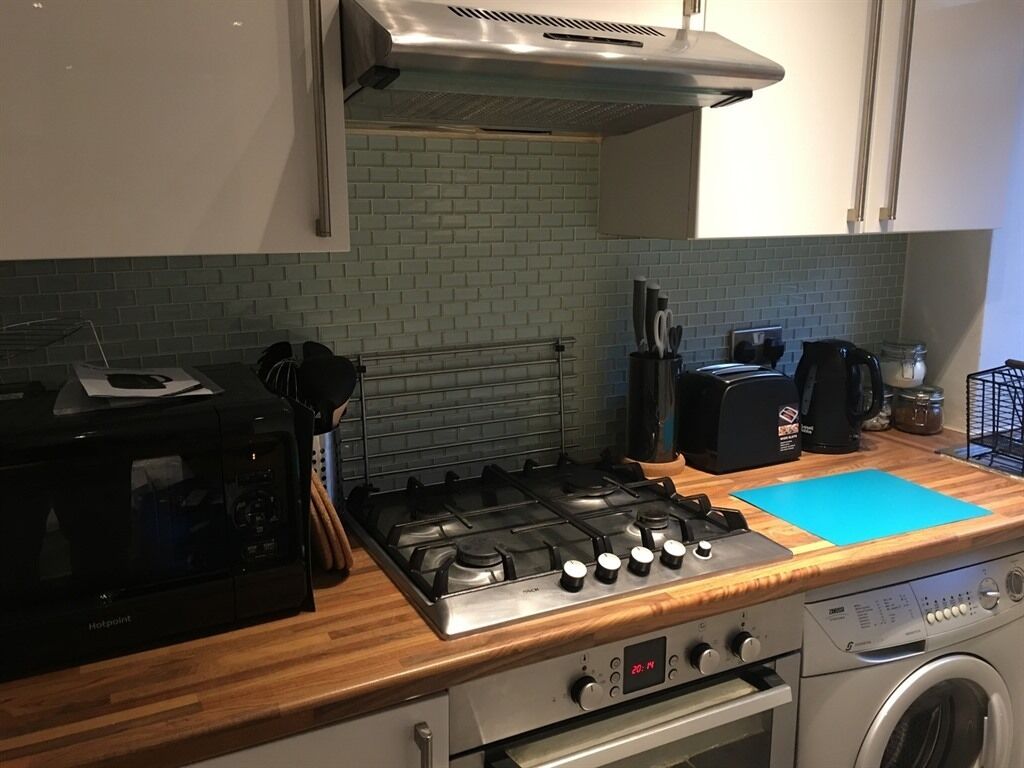 A kitchen with a gas stove, microwave, and a washing machine.