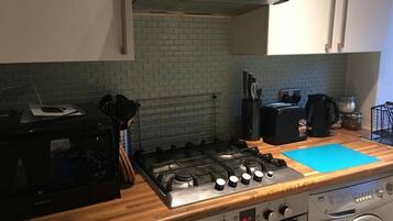A kitchen with a gas stove, microwave, and a washing machine.