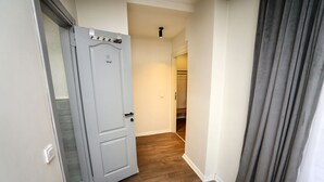 A hallway with a wooden floor, a white door, and a grey curtain. - Arkem Maltepe (Istanbul)