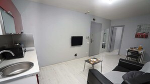 A modern living room with a sofa, a small table, and a TV mounted on the wall. - Arkem Maltepe (Istanbul)