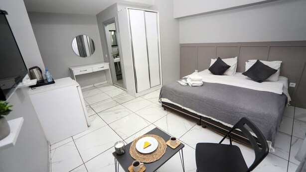 A modern hotel room with a bed, bedside table, chair, and a small table with a plate and cups. - Arkem Maltepe (Istanbul)