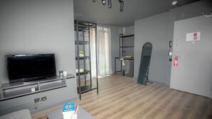 Una sala de estar moderna con un televisor de pantalla plana, un sofá gris y una mesita con un libro y una taza.