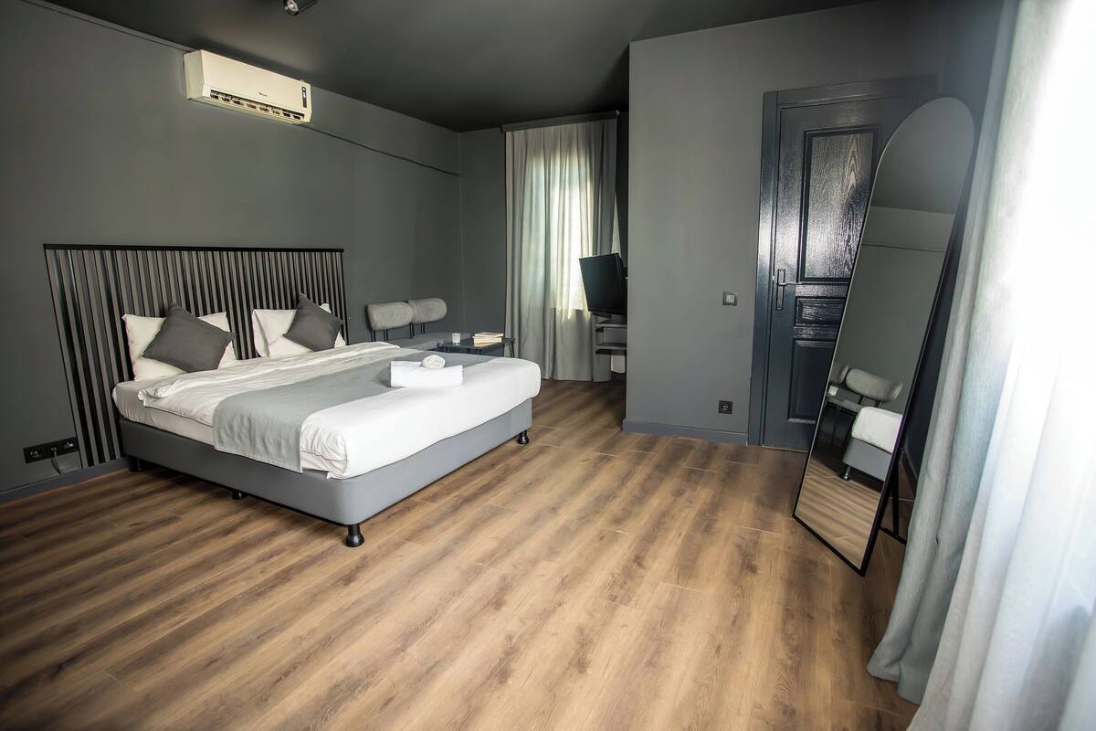 Moderni hotellihuone, jossa on suuri sänky, työpöytä ja peili.