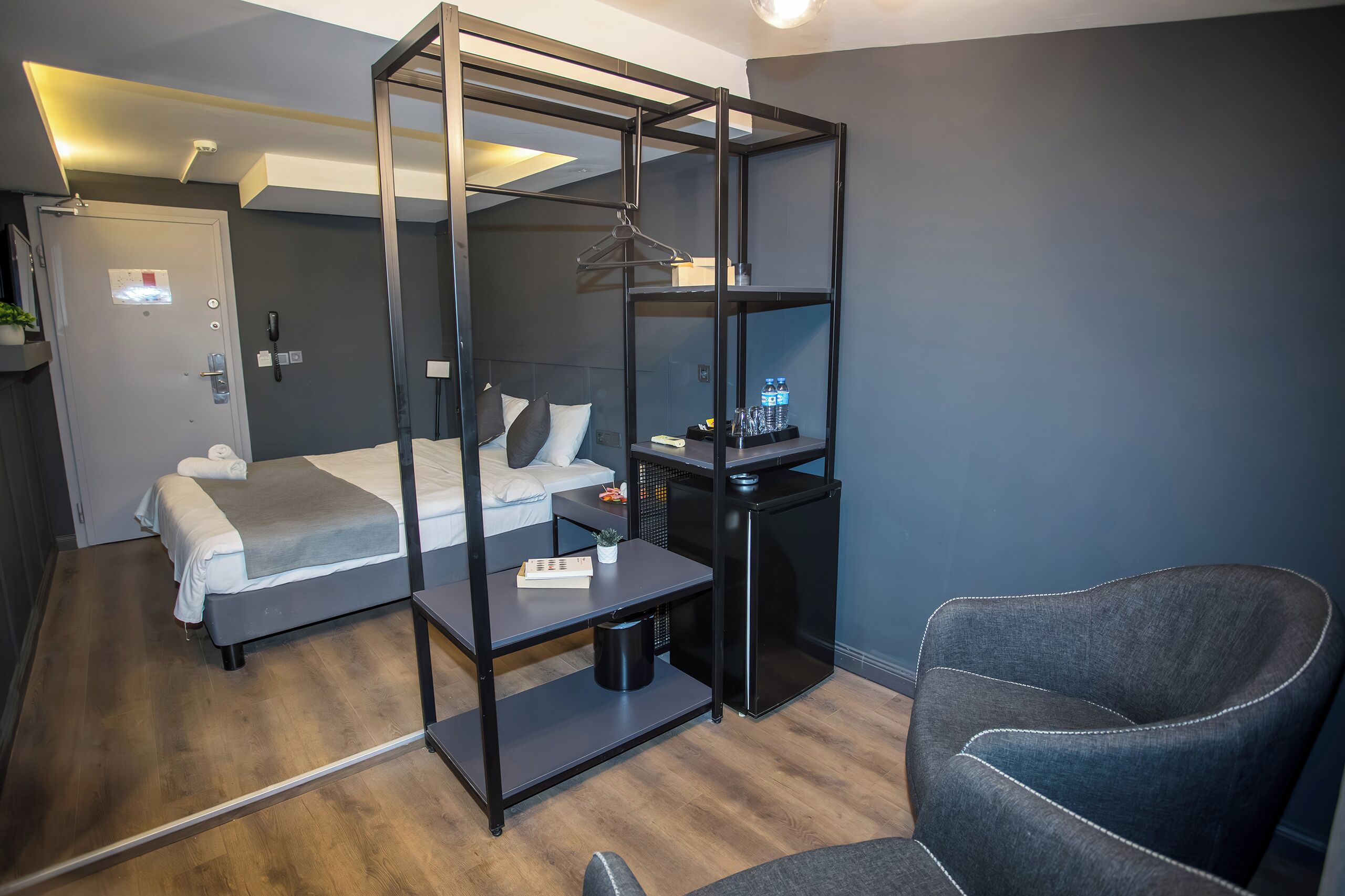Ett modernt hotellrum med en säng, ett skrivbord, en stol och en garderob.