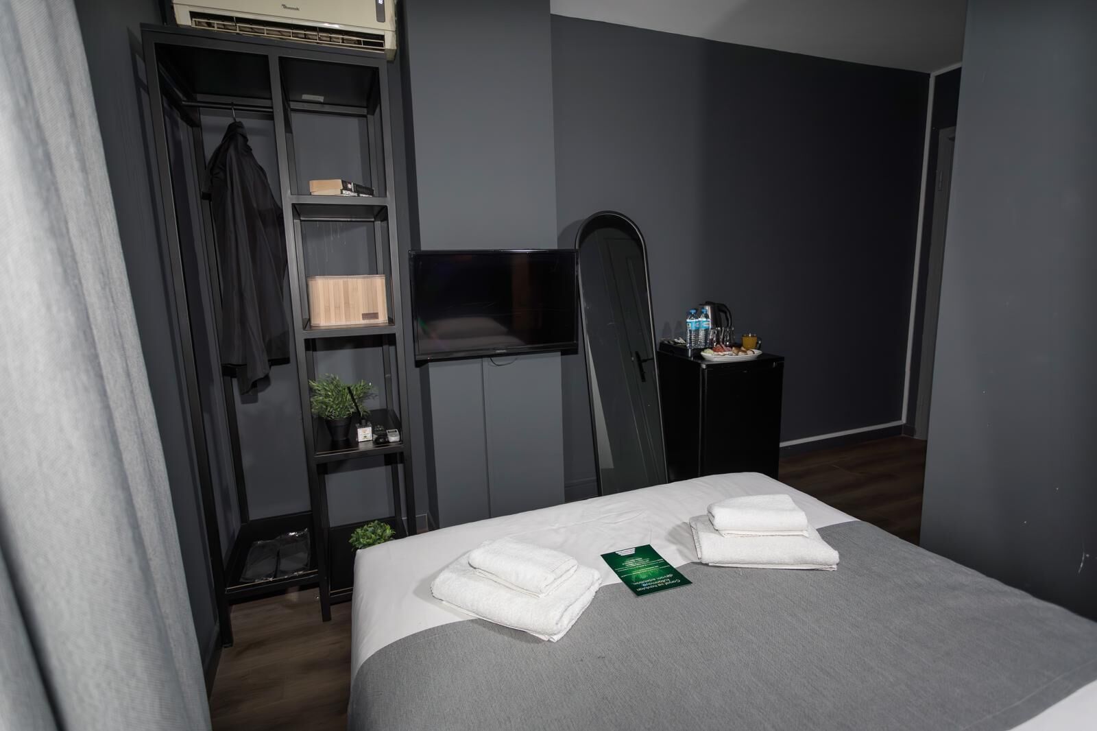 A hotel room with a bed, a wardrobe, a desk, and a television.