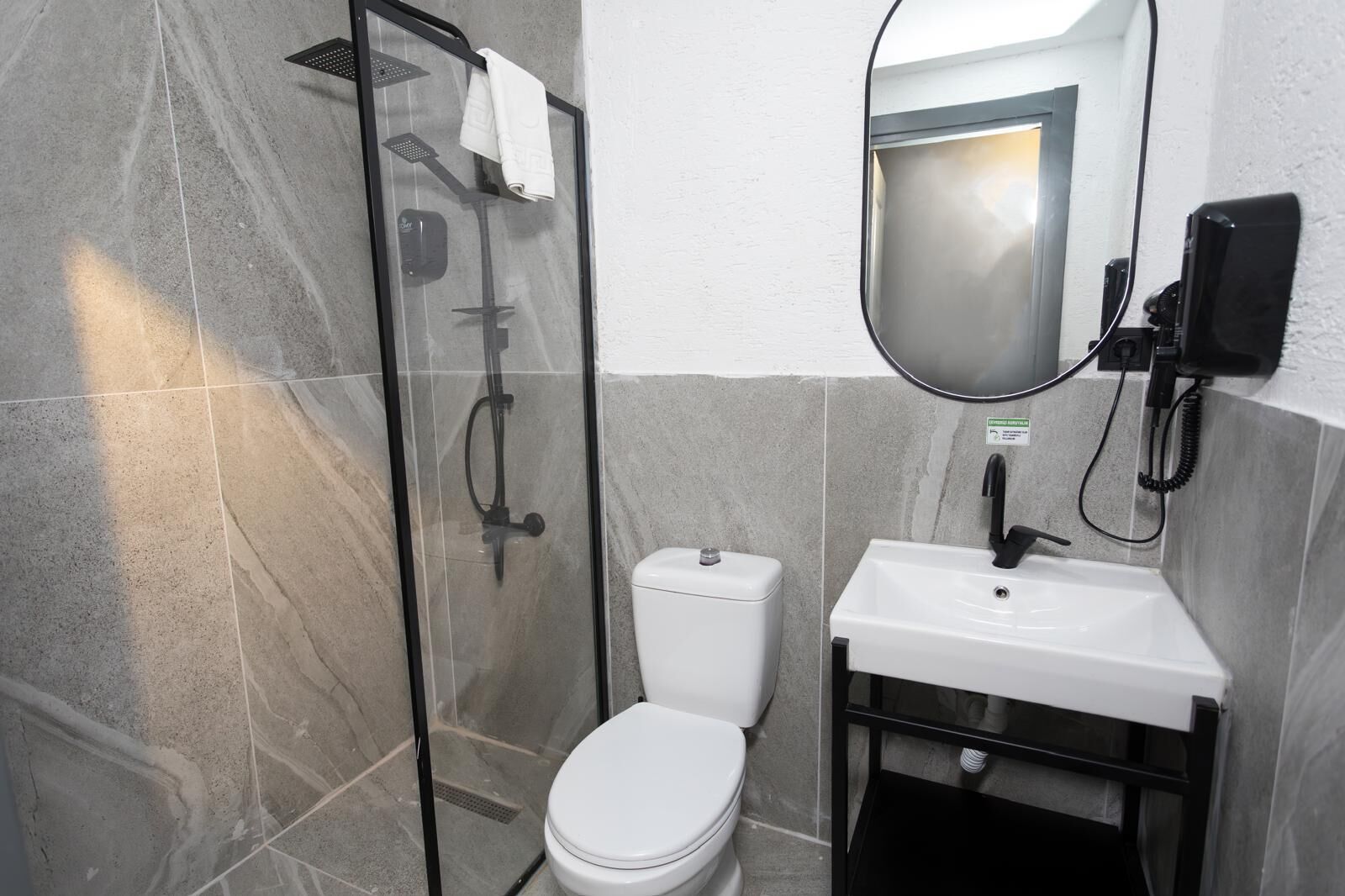 A bathroom with a glass-enclosed shower, a white toilet, and a sink with a mirror above it.