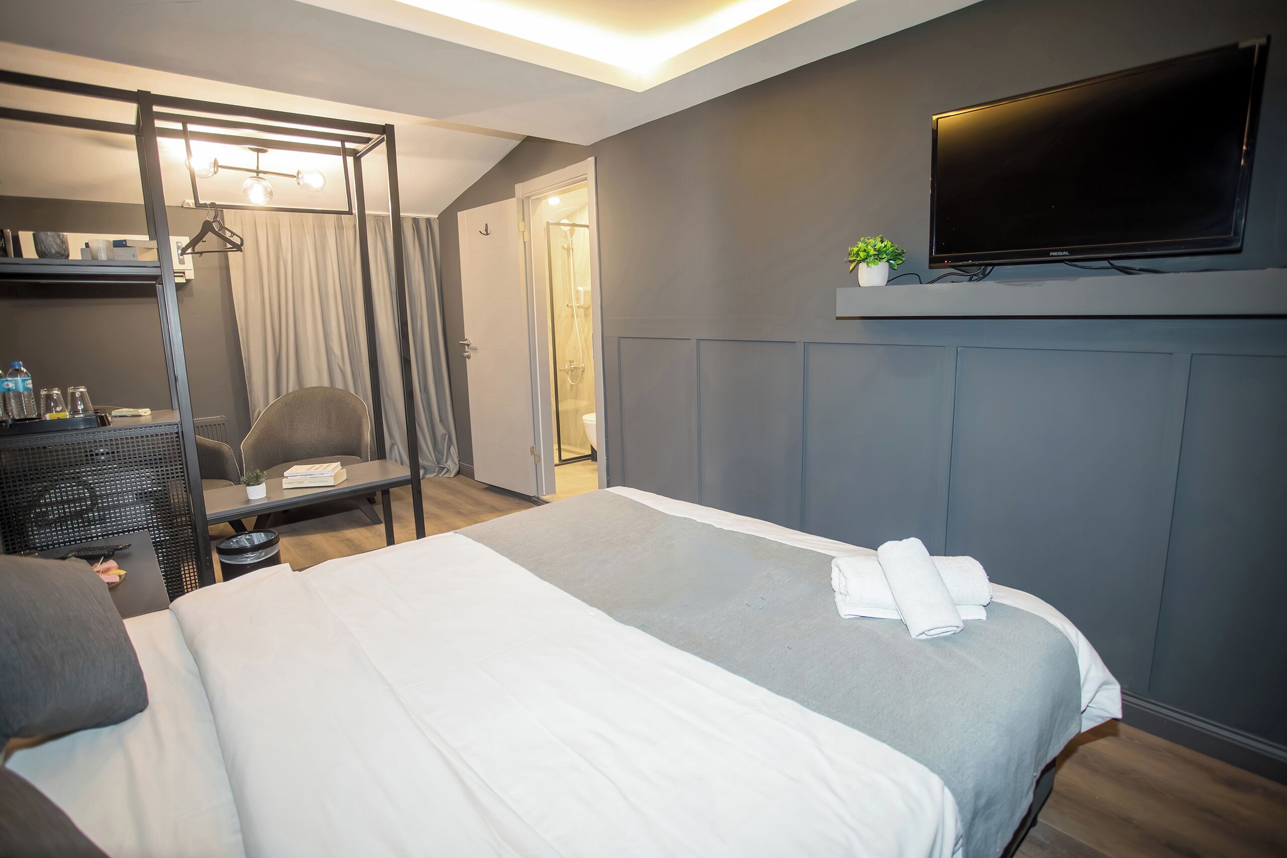 Ein Hotelzimmer mit Bett, Schreibtisch, Sessel, Fernseher und Kleiderschrank.