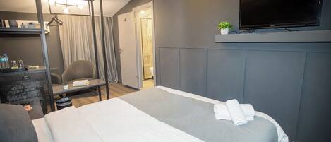 Ein Hotelzimmer mit Bett, Schreibtisch, Sessel, Fernseher und Kleiderschrank.