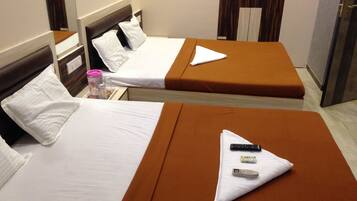 Two single beds with brown headboards and white bedding, a bedside table with a pink container, and a door with a mirror.