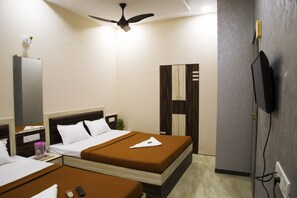 Une chambre d’hôtel avec deux lits, un ventilateur de plafond, une télévision et un mini-bar.