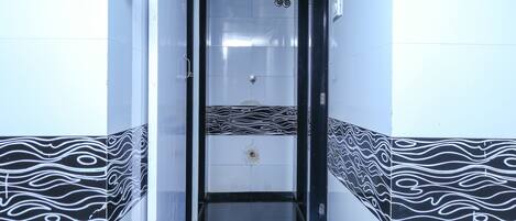 A narrow hallway with black and white patterned walls, a tiled floor, and a door at the end.