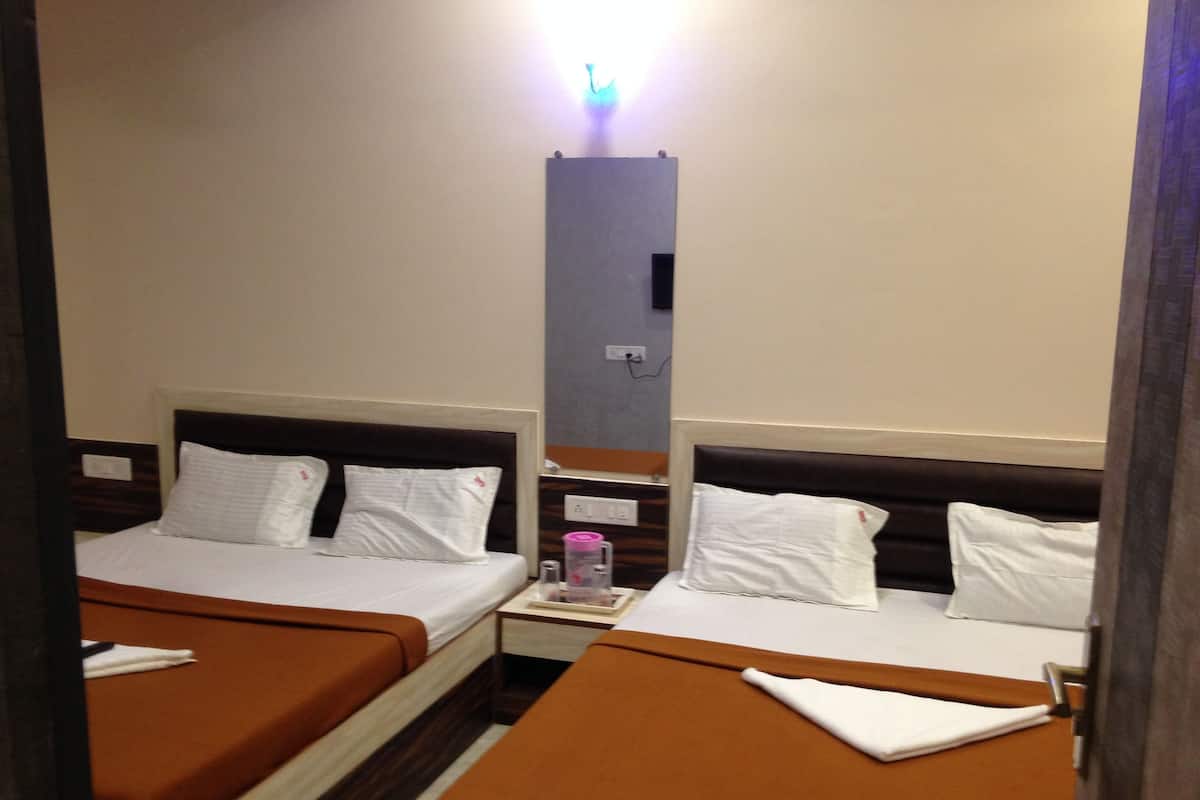 A hotel room with two beds, each with white linens and brown headboards.